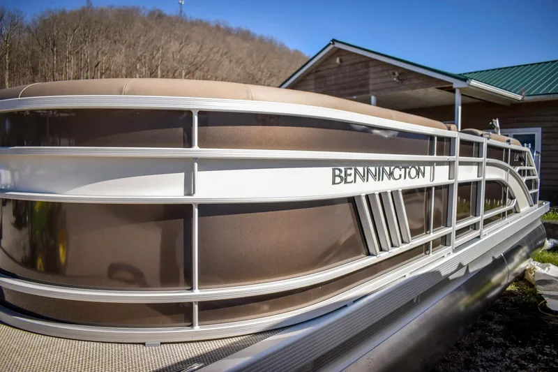 Slide: The Image of 2024 Bennington 22 LSB pontoon boat docked near a wooden building. - 12