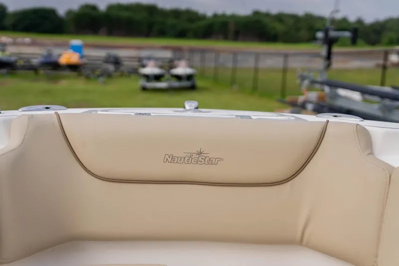 Slide: The Image of NauticStar 2102 Legacy 2022 boat interior with beige seating, outdoor background. - 15