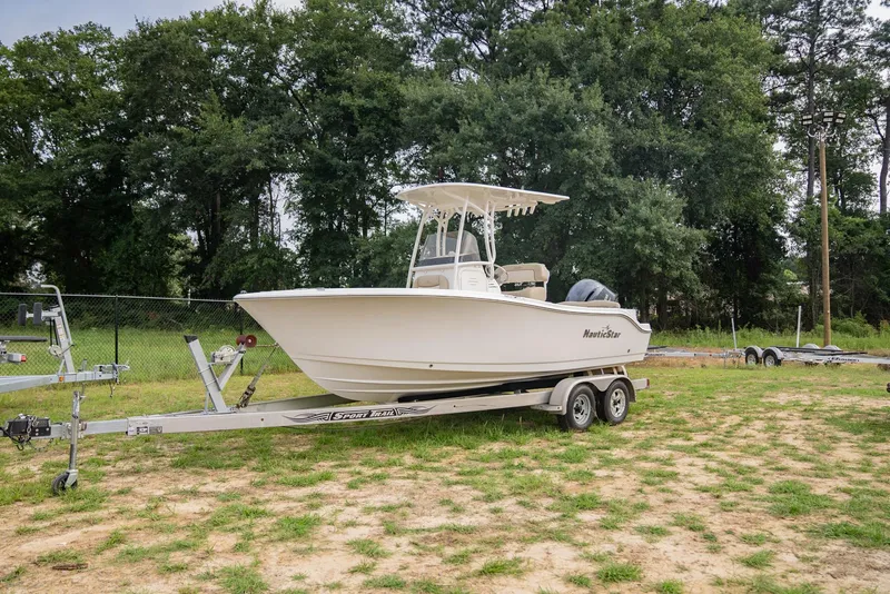 Slide: The Image of 2022 NauticStar 2102 Legacy boat on trailer, parked on grassy area. - 26