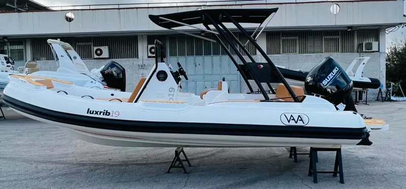 Slide: The Image of 2025 Aqvaboats Luxrib 19 inflatable boat with Suzuki outboard motor, displayed on stands. - 17