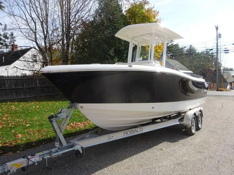 Slide: The Image of 2024 Robalo R230 boat on trailer, parked on a residential street. - 1