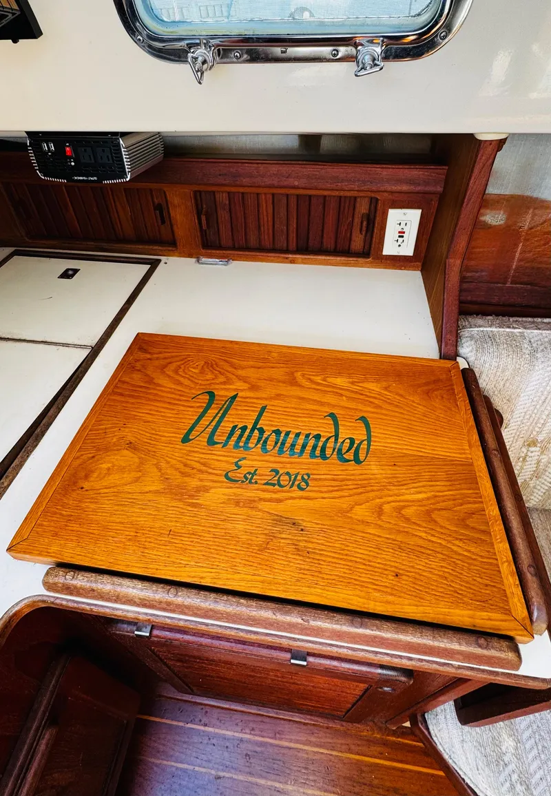 Slide: The Image of Interior of 1987 Island Packet 27 sailboat with wooden surface labeled "Unbounded Est. 2018". - 43