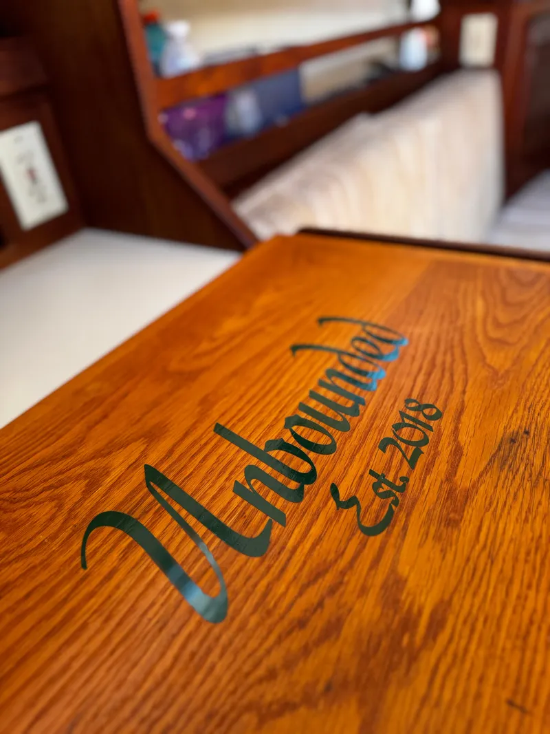 Slide: The Image of Interior of 1987 Island Packet 27 sailboat with "Unbound Est. 2018" on wooden surface. - 44