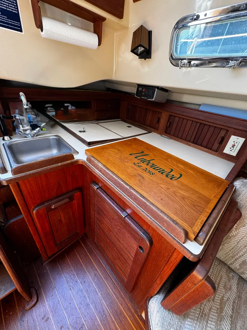 Slide: The Image of 1987 Island Packet 27 sailboat galley with wooden cabinetry and stainless steel sink. - 45
