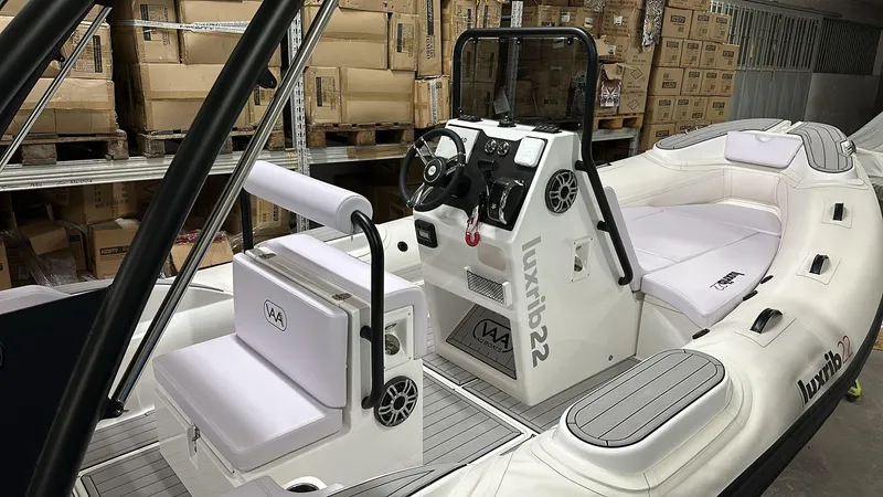 Slide: The Image of 2025 Aqvaboats Luxrib 22 inflatable boat with white seating and control console in warehouse. - 23