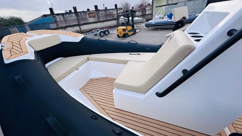 Slide: The Image of 2025 Aqvaboats Luxrib 22 with sleek seating and modern design in a boatyard setting. - 30