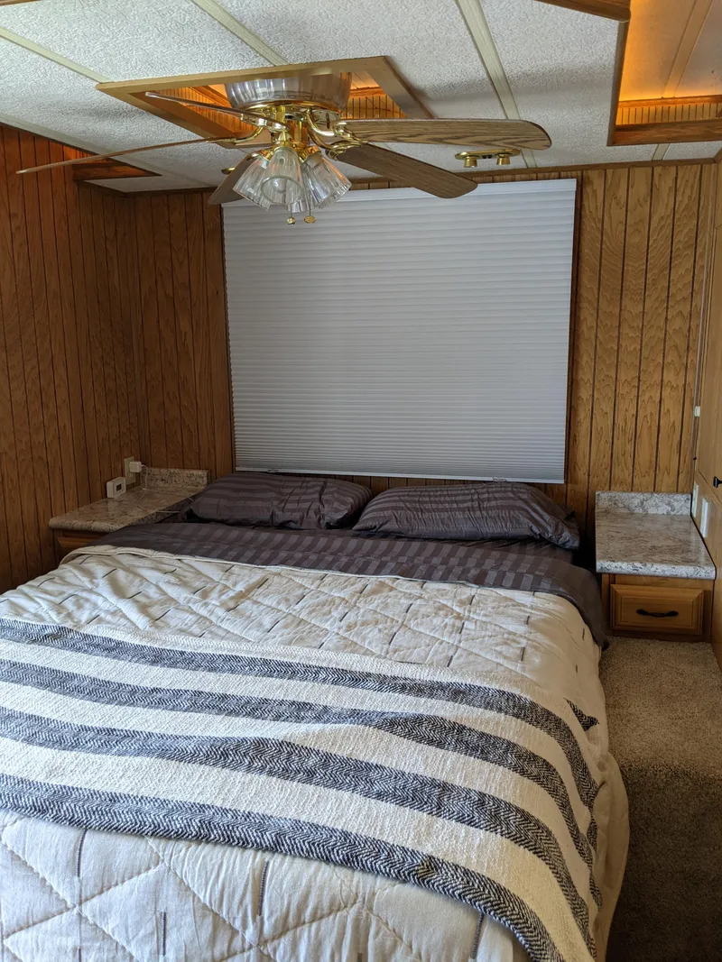 Slide: The Image of Bedroom interior of a 2001 Monticello River Yacht with wood paneling and a ceiling fan. - 22