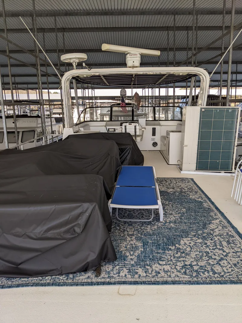 Slide: The Image of 2001 Monticello River Yacht docked, featuring covered seating and blue lounge chair on deck. - 41