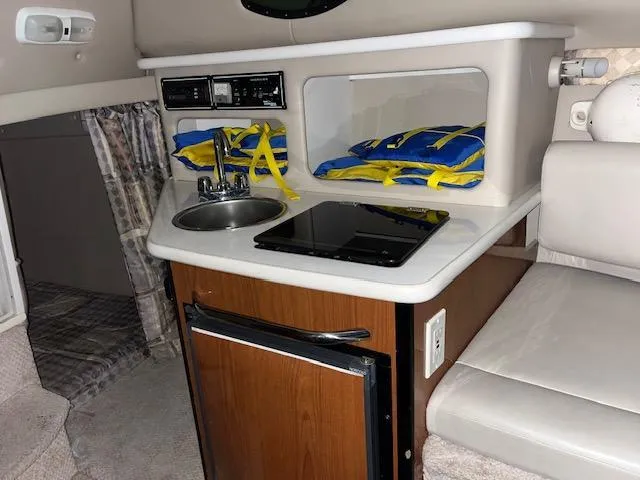 Slide: The Image of Compact kitchen area in a 2000 Chaparral 240 Signature boat with sink, stove, and life jackets. - 9