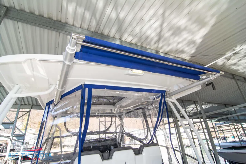 Slide: The Image of 2020 Jeanneau Leader 10.5 boat with blue canopy under a metal roof. - 45