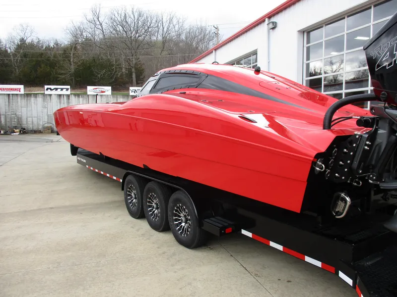 Slide: The Image of 2023 MTI 390XR red powerboat on a triple-axle trailer outside a garage. - 3