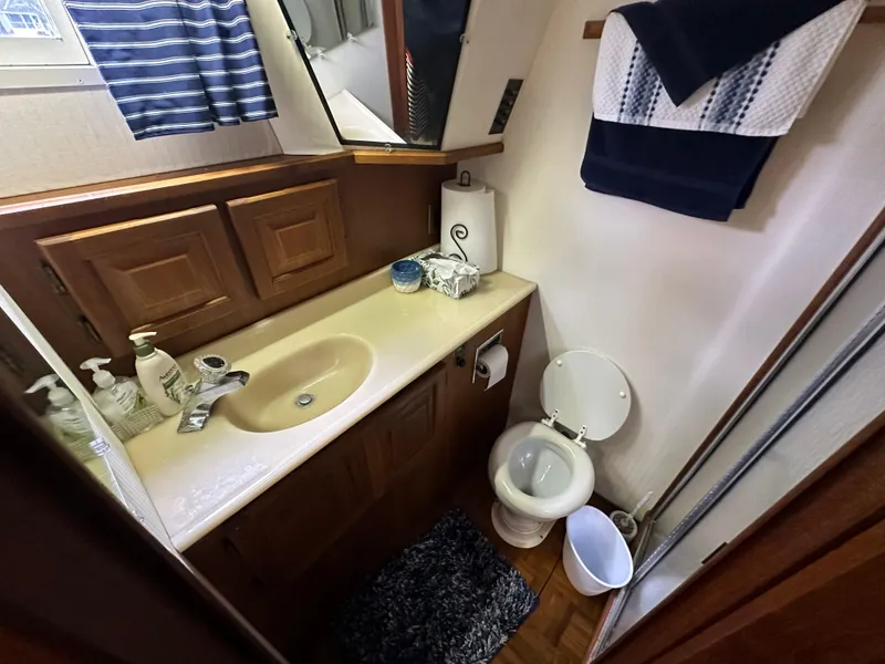 Slide: The Image of 1987 Viking Boats 44 Motor Yacht bathroom with sink, toilet, and wooden cabinetry. - 34