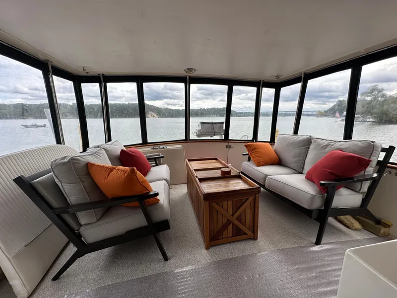 Slide: The Image of 1987 Viking Boats 44 Motor Yacht interior with lake view, featuring comfortable seating and a wooden table. - 38
