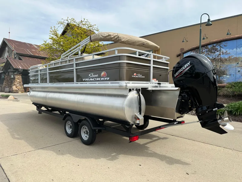 Slide: The Image of 2024 Sun Tracker SportFish 22 XP3 pontoon boat on trailer with Mercury outboard motor. - 2
