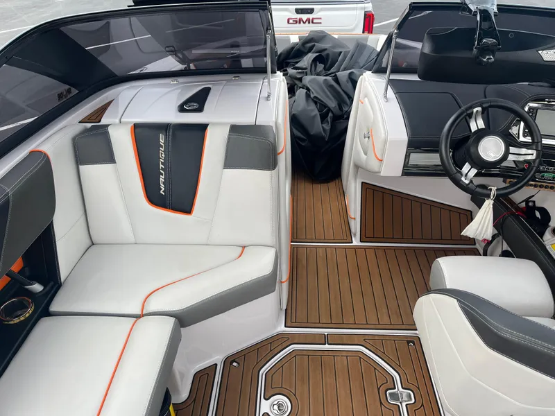 Slide: The Image of 2013 Nautique G23 boat interior with white and gray seating, wood flooring, and a GMC truck in the background. - 10