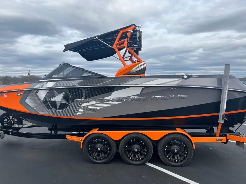 Slide: The Image of 2013 Nautique G23 boat with orange and black design on a triple-axle trailer. - 6