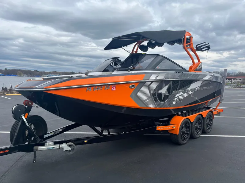 Slide: The Image of 2013 Nautique G23 boat with orange and black design on a trailer. - 7
