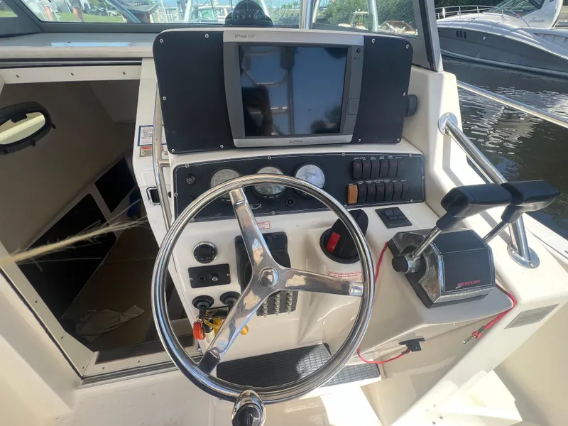 Slide: The Image of 2003 Boston Whaler 290 Outrage boat helm with steering wheel and control panel. - 4
