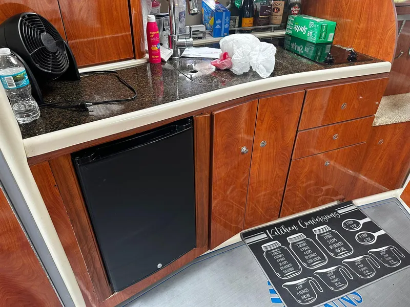 Slide: The Image of 2006 Four Winns 328 Vista boat kitchen with wooden cabinets, mini fridge, and countertop items. - 29