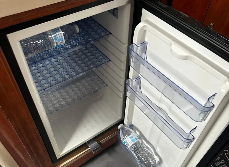 Slide: The Image of Open mini fridge with water bottles inside on a 2006 Four Winns 328 Vista boat. - 32