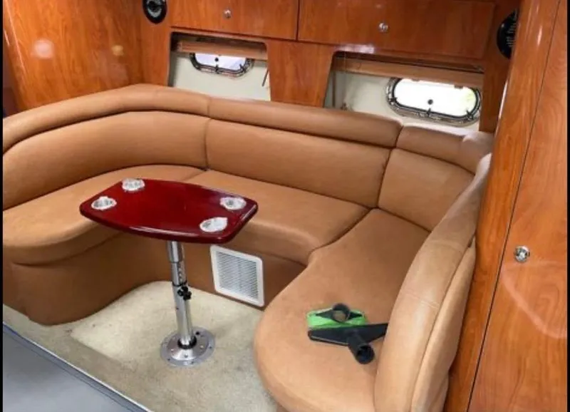 Slide: The Image of 2006 Four Winns 328 Vista cabin interior with tan seating and wooden table. - 33