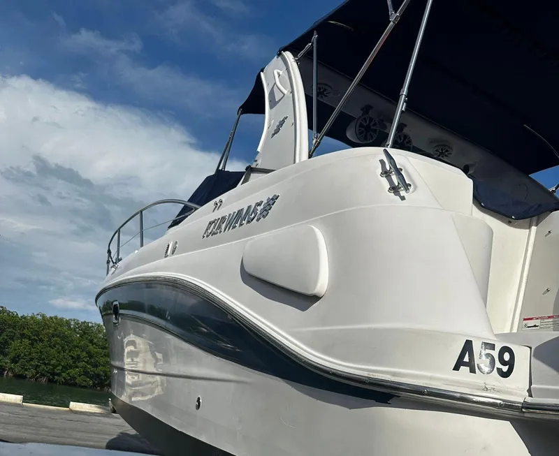 Slide: The Image of 2006 Four Winns 328 Vista boat docked, white hull, blue canopy, clear sky background. - 9