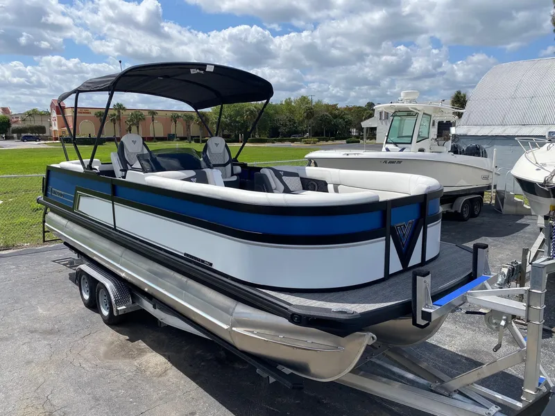 Slide: The Image of 2024 Viaggio Diamante 24U pontoon boat on a trailer under a partly cloudy sky. - 1