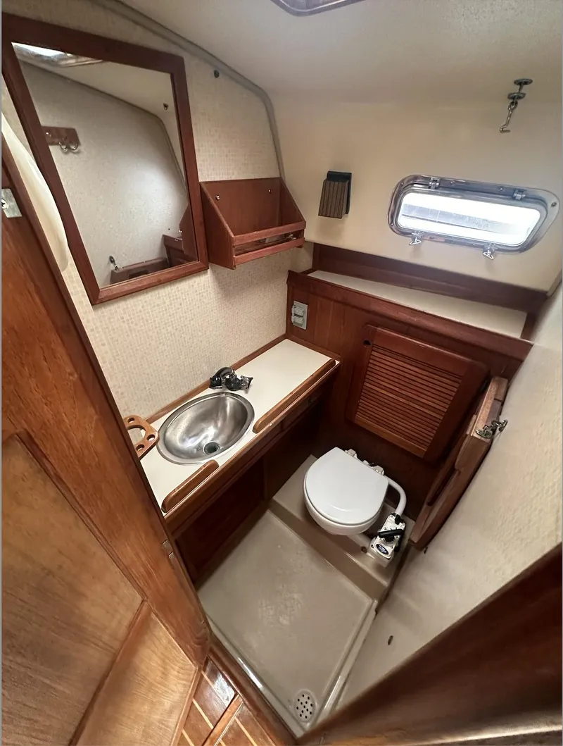 Slide: The Image of 1990 Island Packet 27 sailboat bathroom with sink, toilet, and wooden cabinetry. - 10