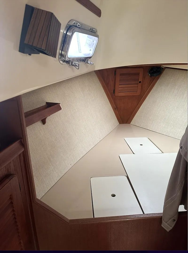 Slide: The Image of Interior cabin of a 1990 Island Packet 27 sailboat, featuring wood accents and a porthole. - 12