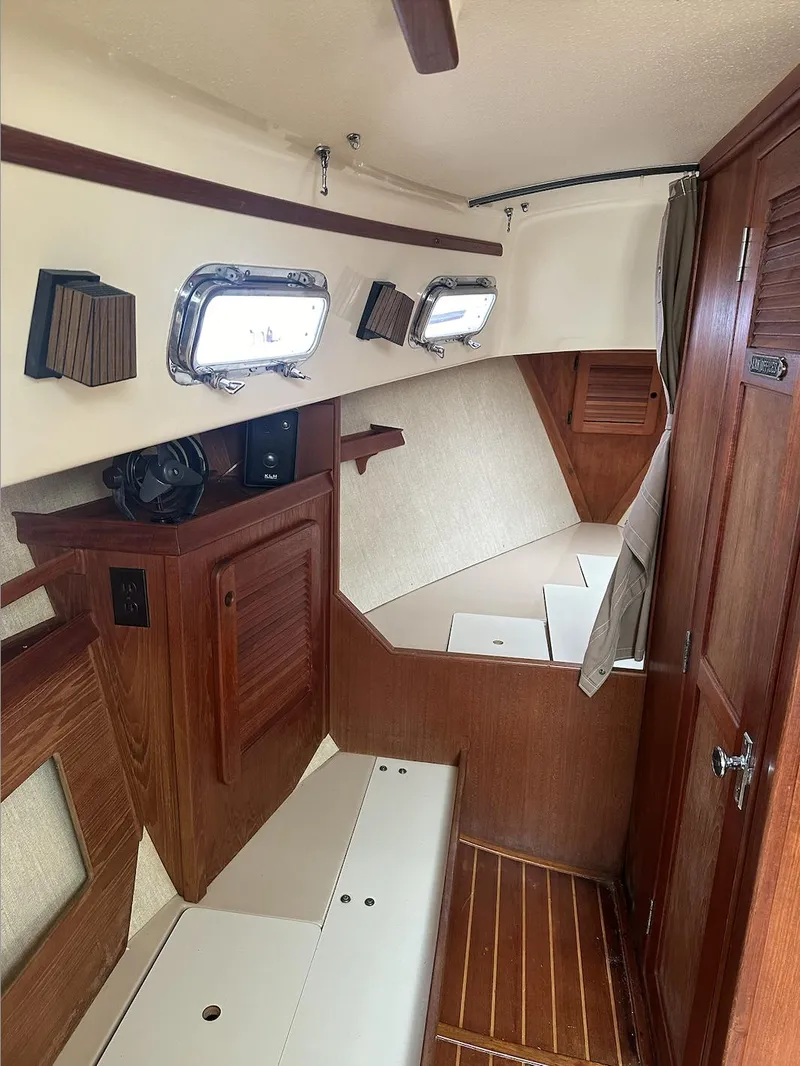 Slide: The Image of 1990 Island Packet 27 sailboat interior with wood finish and portholes. - 13