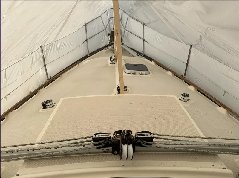 Slide: The Image of 1990 Island Packet 27 sailboat under protective cover, showcasing deck and rigging. - 20