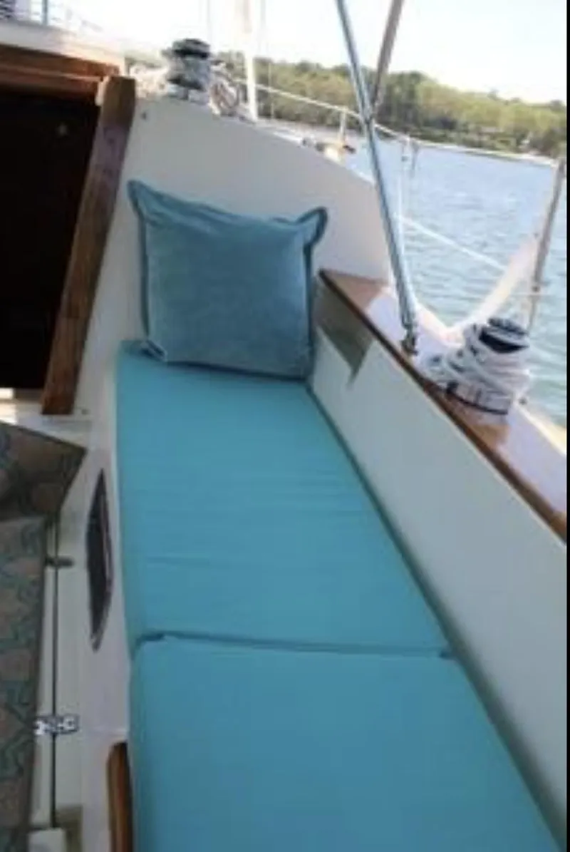 Slide: The Image of 1990 Island Packet 27 sailboat with blue cushioned seating on deck. - 4