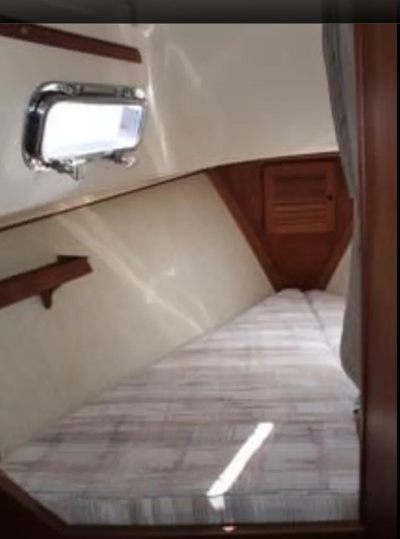 Slide: The Image of 1990 Island Packet 27 cabin interior with bed and porthole window. - 6