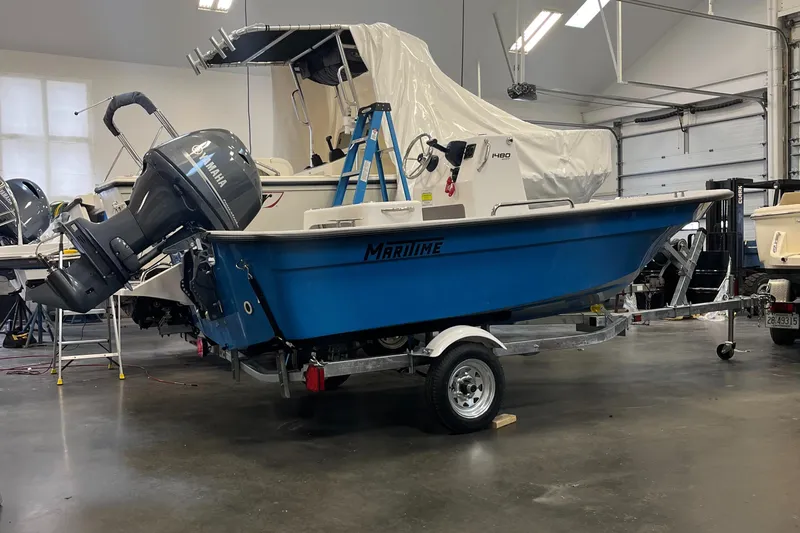 Slide: The Image of 2024 Maritime 1480 Skiff boat in a garage, blue hull, on a trailer. - 3