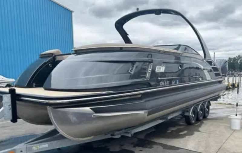 The Image of 2022 Bennington 27 QX pontoon boat on a trailer at a marina. - 0