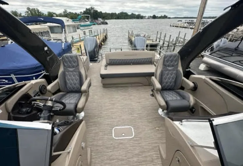Slide: The Image of 2022 Bennington 27 QX boat interior with luxurious seating at a marina. - 3