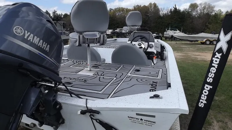 Slide: The Image of 2021 Xpress XP7 boat with Yamaha outboard motor, parked on grass. - 13