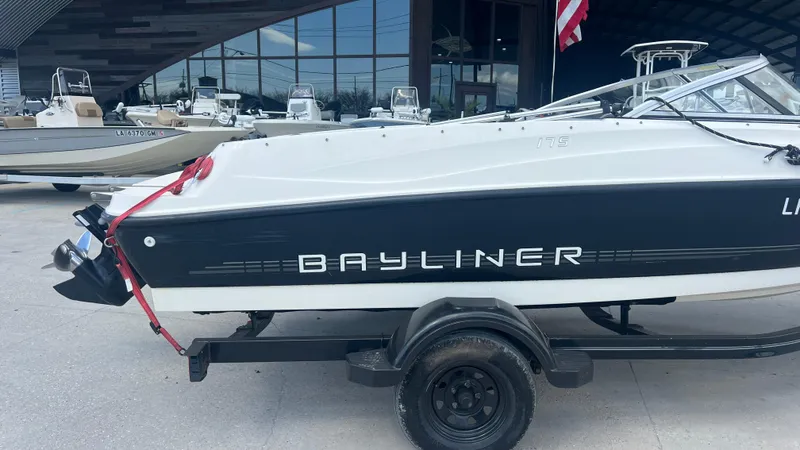 Slide: The Image of 2012 Bayliner 175 Bowrider boat on a trailer outside a showroom. - 9