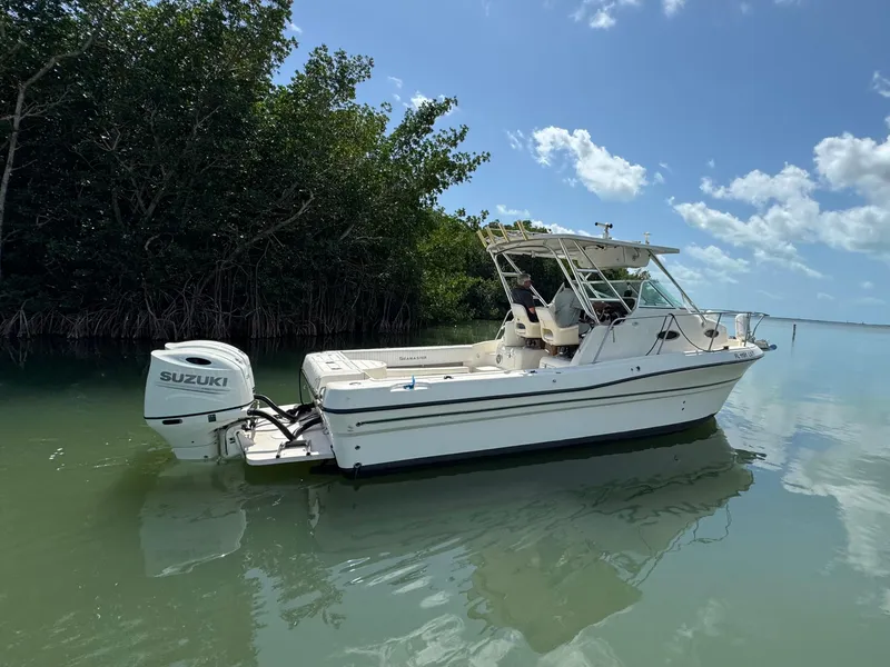 Slide: The Image of 2002 Seamaster 2800 Walkaround boat with Suzuki outboard motor on calm water. - 2