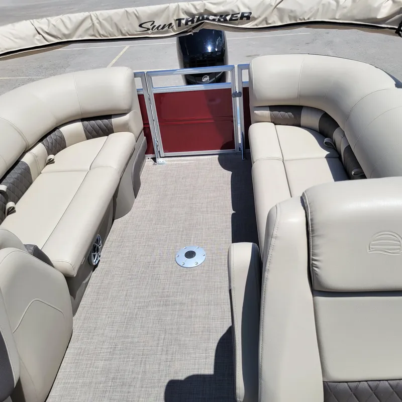 Slide: The Image of 2024 Sun Tracker Party Barge 24 DLX interior with beige seating and spacious layout. - 2
