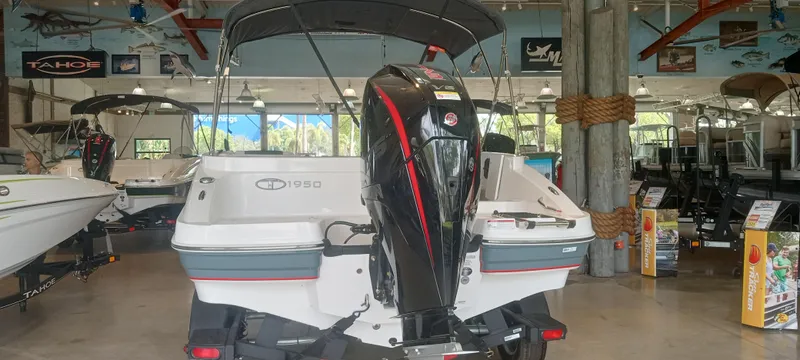 Slide: The Image of 2024 Tahoe 1950 boat displayed in showroom, rear view with motor. - 3
