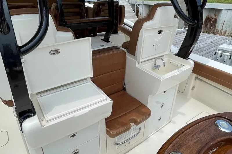 Slide: The Image of 2020 Scout 420 LXF boat interior with brown leather seats and white cabinetry. - 49