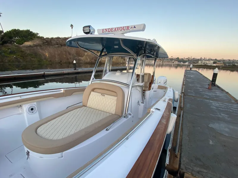 Slide: The Image of 2025 Mag Bay 33 CC boat docked, featuring a cushioned seating area and sleek design. - 13