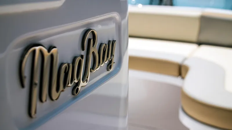Slide: The Image of Close-up of 2025 Mag Bay 33 CC boat logo with seating area in background. - 2