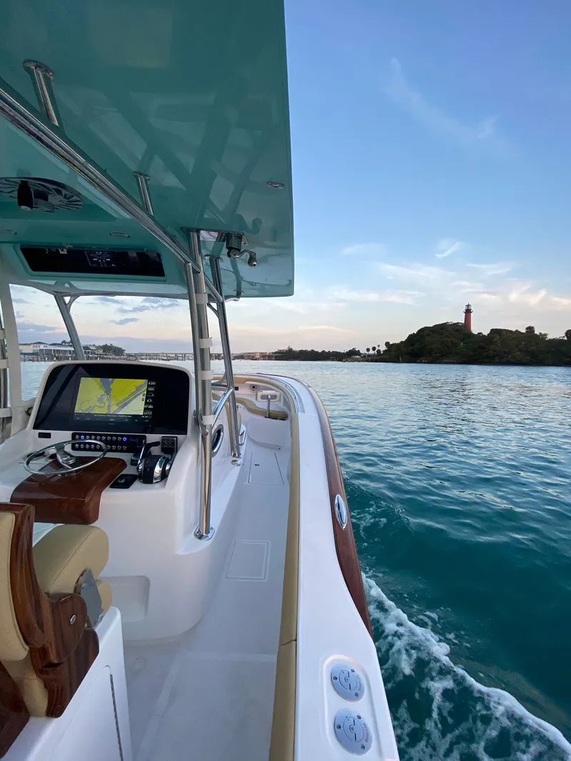 Slide: The Image of 2025 Mag Bay 33 CC boat cruising on calm waters near a lighthouse. - 7