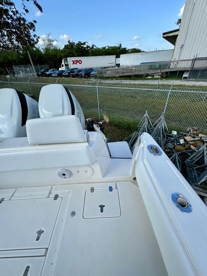 Slide: The Image of 2007 Intrepid 350 Walkaround boat with dual outboard engines, docked near a fence. - 21