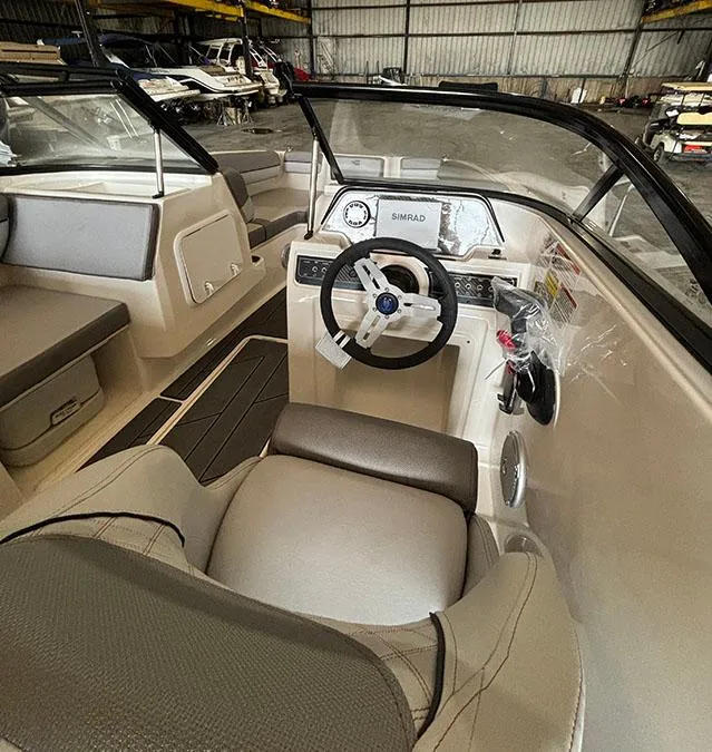 Slide: The Image of 2024 Bayliner DX2000 boat interior with steering wheel and dashboard in a warehouse. - 10