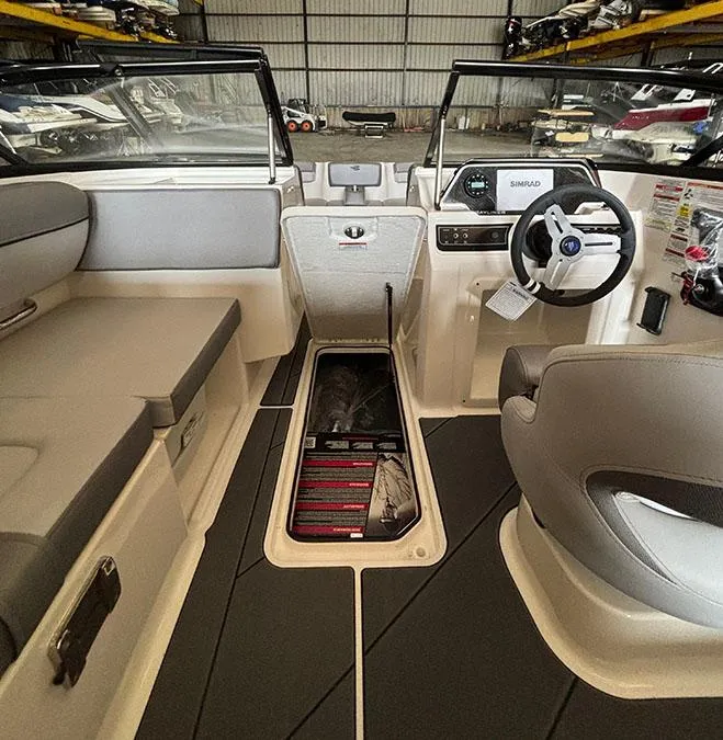 Slide: The Image of 2024 Bayliner DX2000 boat interior with seating, steering wheel, and storage compartment. - 14