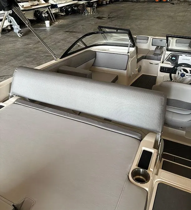 Slide: The Image of 2024 Bayliner DX2000 boat interior with seating and steering console in a warehouse. - 8