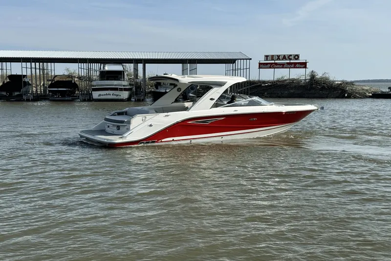 Slide: The Image of 2021 Sea Ray 310 SLX boat cruising on a lake near a marina. - 2